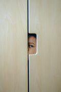 Enfant caché derrière une porte – illustration de la peur ou de la vulnérabilité en contexte familial