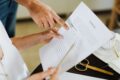 Deux personnes relisant un contrat annoté au stylo, illustration de la relecture de l’acte liquidatif et de la convention de divorce