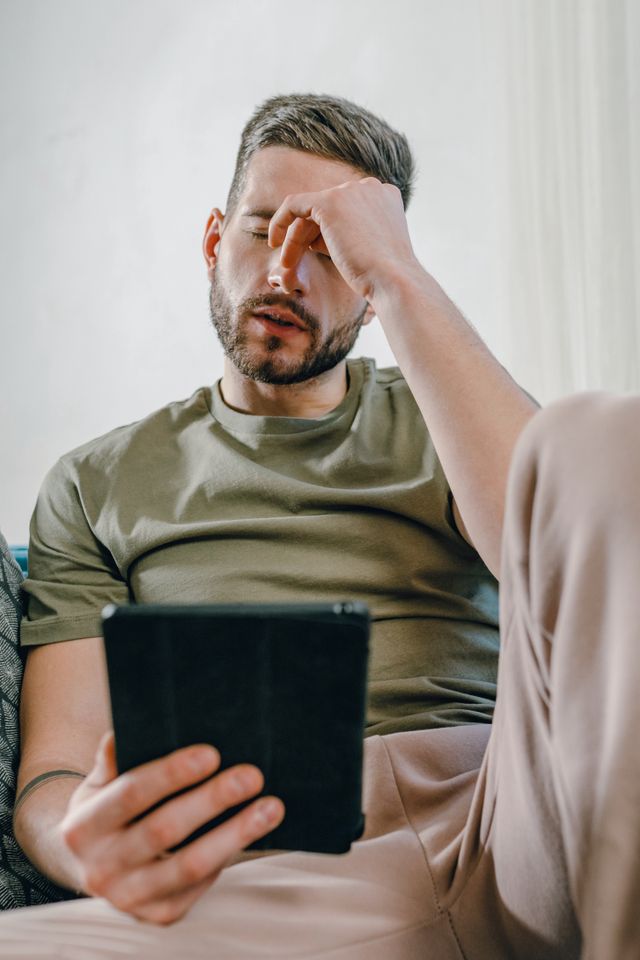 Homme préoccupé, la main sur le front, découvrant sur sa tablette une assignation en ordonnance de protection